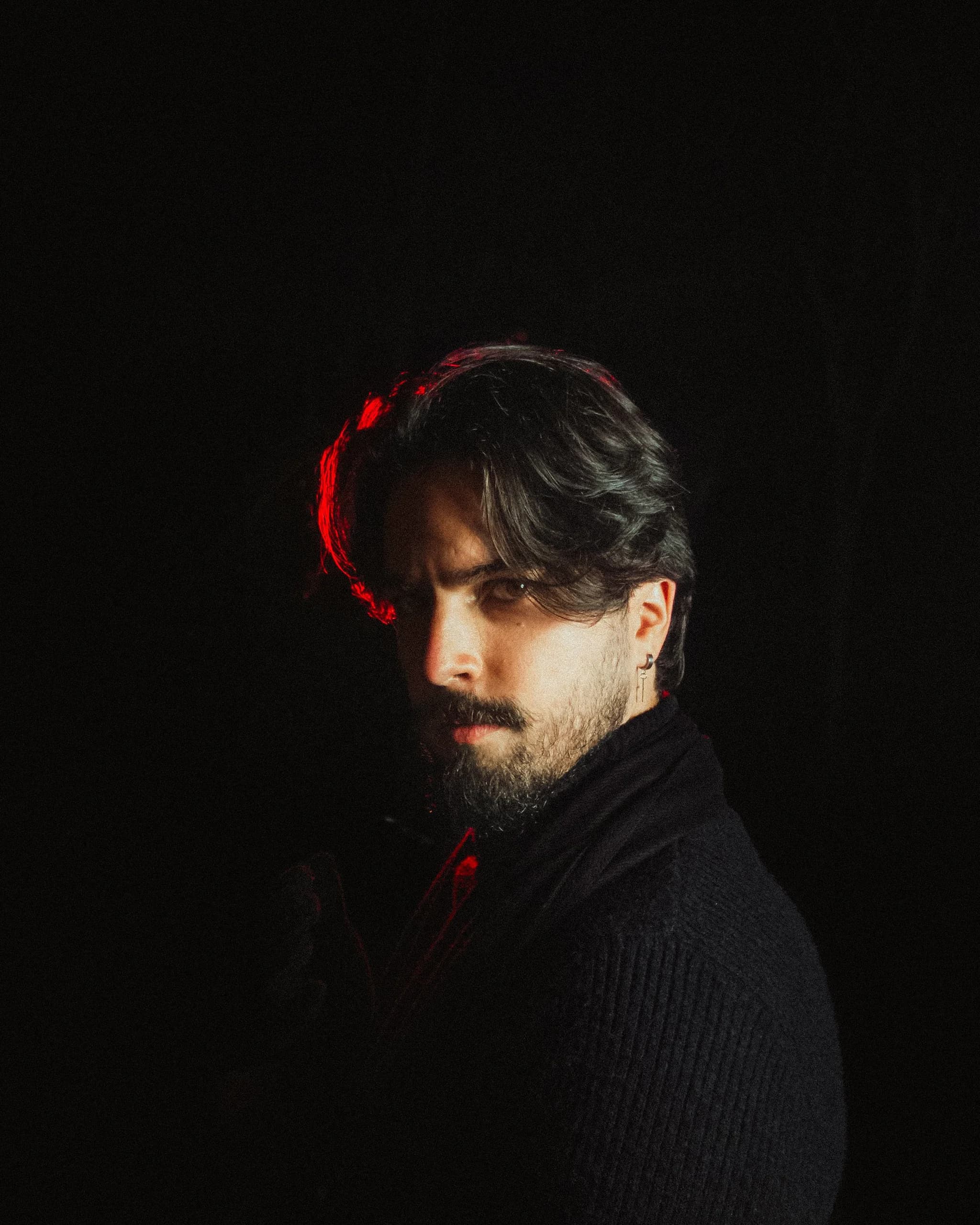 A portrait lit by a single practical lamp just out of frame, steep falloff into darkness, 85mm, shallow focus